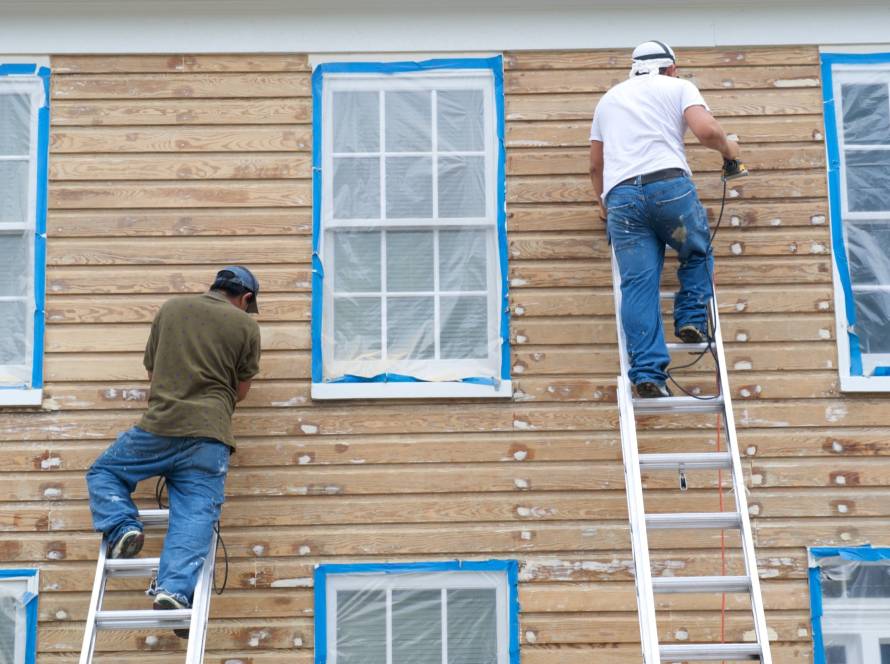 Painting crew working on house siding with ladders