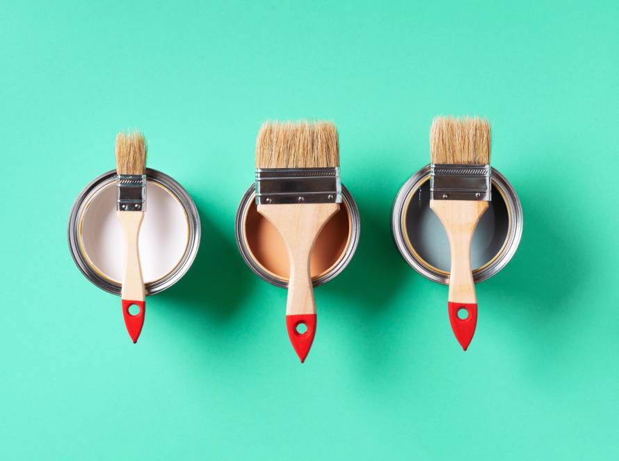 Paint brushes resting on colorful paint can lids