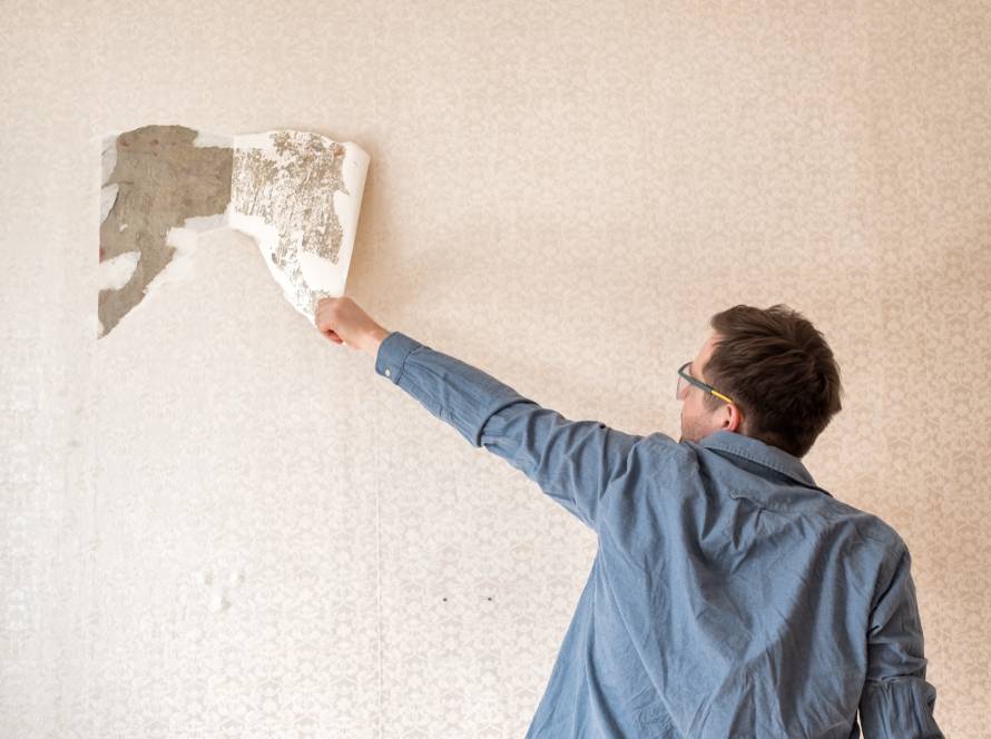 Painter removing old wallpaper from a wall