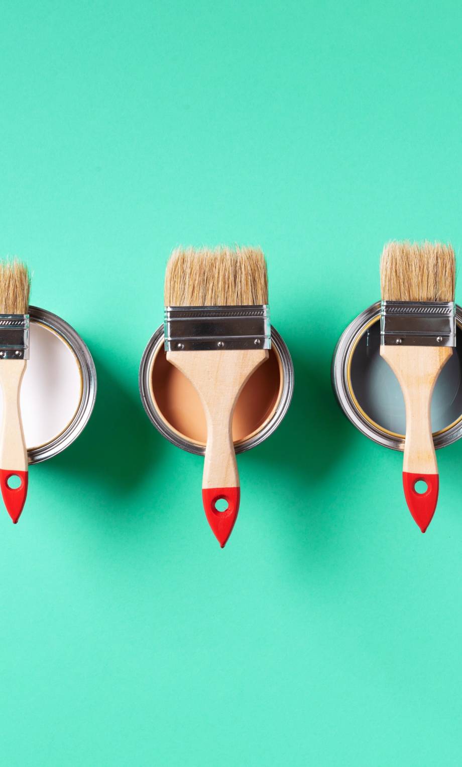 Paint brushes resting on colorful paint can lids